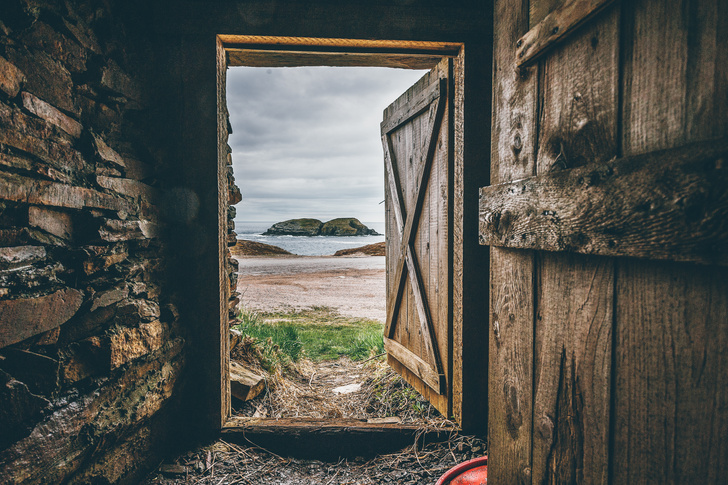 Brown wooden door opening out onto a beach view